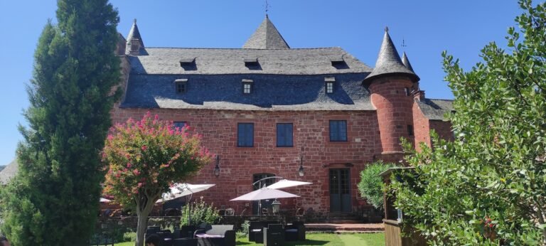 Château historique en grès rouge avec poivrières et terrasse aménagée avec parasols pour une réception de mariage avec une wedding planner de Seine-et-Marne