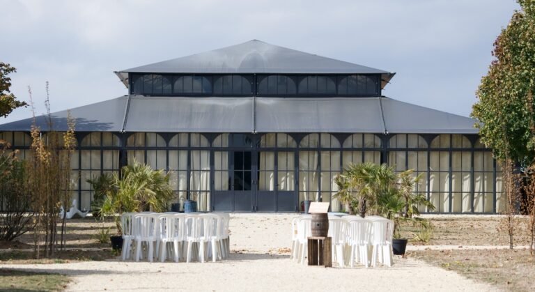 Vue extérieure de la structure vitrée du Domaine d'Aliénor et son allée aménagée pour un mariage.Lieu de réception de mariage par votre wedding planner en Seine-et-Marne